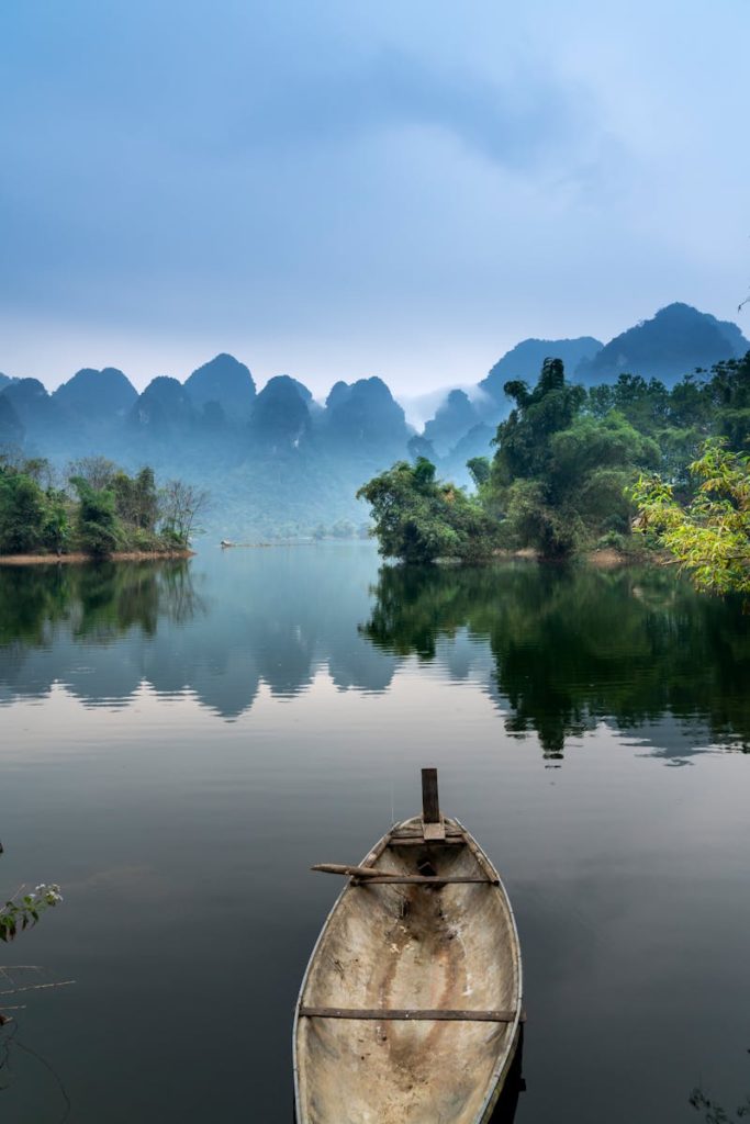 A tranquil river scene with a canoe, misty mountains, and lush greenery, perfect for nature lovers.